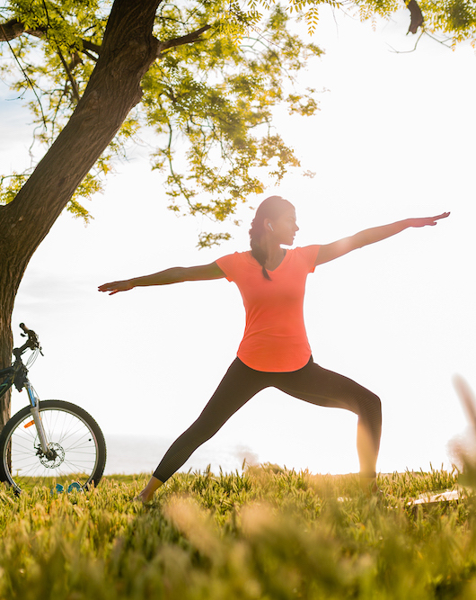 slim beautiful woman silhouette doing sports in morning in park doing yoga on mat in colorful fitness outfit in nature, smiling happy healthy lifestyle, calm meditation, bicycle on background health coaching for chronic illness